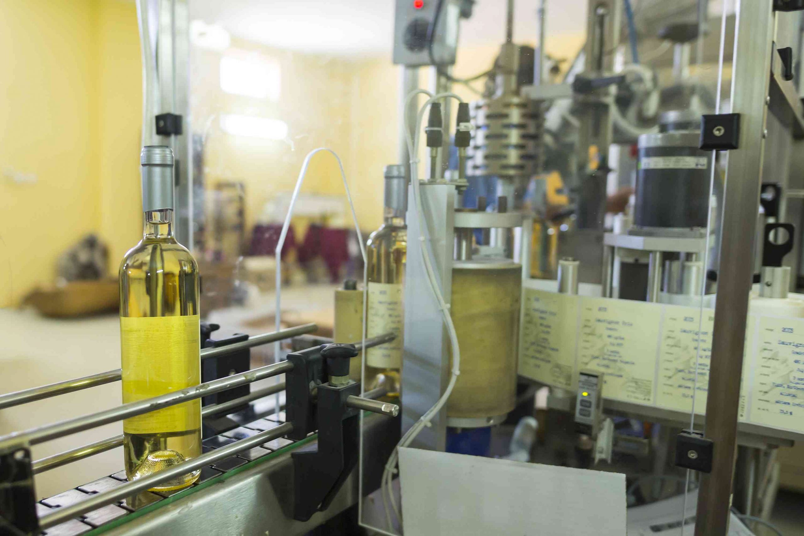 Wine bottles moving through a labelling process machine at a winery